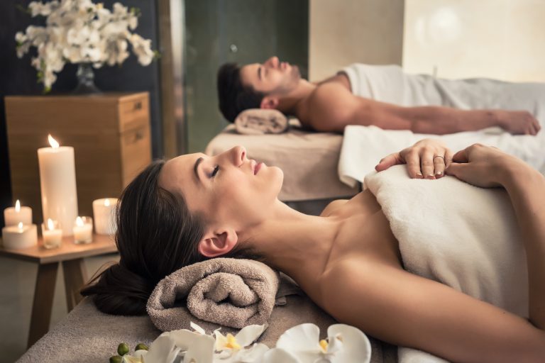 Young man and woman lying down on massage beds at Asian luxury spa and wellness center